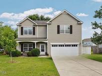Charming two-story home featuring a well-maintained lawn and a two-car garage with ample parking space at 6001 Winged Willet Ct, Wendell, NC 27591