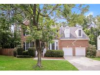 Charming two-story brick home features a well-manicured lawn, mature trees, and a two-car garage at 616 Cheselden Dr, Durham, NC 27713