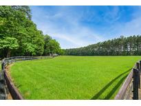 Expansive green pasture bordered by mature trees and a classic wooden fence at 633 Fleming Rd, Youngsville, NC 27596