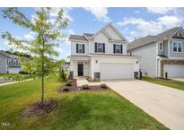 Charming two-story home featuring a two-car garage, manicured lawn, and tasteful landscaping at 80 Nailsworth St, Angier, NC 27501