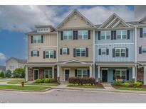 Charming exterior of townhomes with inviting front porches, colorful facades, and manicured landscaping at 996 Tender Dr, Apex, NC 27502