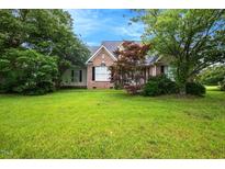 Charming brick home with a lush green lawn and mature trees, offering a serene curb appeal at 1016 Pasture View Ln, Raleigh, NC 27603