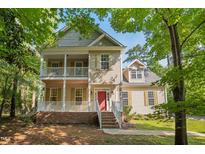 Charming two-story home boasts double front porches, a red front door, and beautifully landscaped surroundings at 2418 Mont Haven Dr, Durham, NC 27712