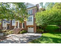 Charming brick townhome with manicured landscaping, a one-car garage, and inviting staircase leading to the front door at 315 Allister Dr, Raleigh, NC 27609