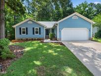 Charming blue home featuring a well-manicured lawn and an attached two-car garage at 3400 Appling Way, Durham, NC 27703