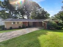 Charming single-story home featuring a brick facade, well-maintained lawn, and a driveway leading to a covered entrance at 3721 Suffolk St, Durham, NC 27707
