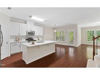 Bright eat-in kitchen featuring white cabinets, stainless steel appliances, and a central island with sink at 5028 Blue Jack Oak Dr, Cary, NC 27519