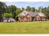 Charming brick home featuring a large lawn, complemented by a two-car garage and an array of mature trees at 6708 Wavcott Dr, Fuquay Varina, NC 27526