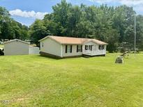 Cozy single-story home with well-maintained lawn, mature trees, and a detached garage at 94 S Waters Edge Ln, Henderson, NC 27537