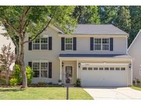 Two-story home with tan siding, black shutters, well-kept lawn, and mature trees at 12320 Tetons Ct, Durham, NC 27703