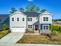 Beautiful two-story home boasts a two-car garage, gray siding, stone accents and manicured lawn at 132 Yellow River Way, Garner, NC 27529