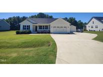 Beautiful single-story home with attached garage and manicured lawn and inviting front porch at 160 Inverness St, Zebulon, NC 27597