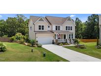 Charming two-story home featuring a manicured lawn, welcoming porch, and attached garage at 185 Twilight Trl, Willow Springs, NC 27592