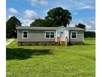 Charming single-story home featuring green lawn, light brown siding, and welcoming front entrance at 2232 Tarboro Road Rd, Youngsville, NC 27596