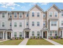 Charming townhomes boast diverse siding, manicured lawns, and inviting walkways under a partly cloudy blue sky at 2708 Chert Ln, Raleigh, NC 27610