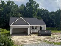 A newly built home with a gray exterior, an open garage and a dark roof with some landscaping to be completed at 2776 Rains Mill Rd, Princeton, NC 27569