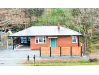 Charming brick home with a vibrant blue front door and a modern metal roof at 2907 University Dr, Durham, NC 27707