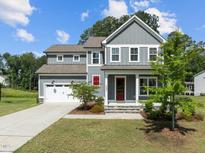 Charming two-story home features a gray exterior, red door, well-manicured lawn, and attached two-car garage at 3053 Roy Ct, Apex, NC 27523
