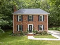 Charming brick home featuring black shutters, a well-manicured lawn, and mature trees offering natural shade at 308 Trappers Sack Rd, Cary, NC 27513