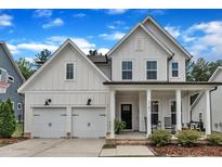 Charming two-story white farmhouse with a welcoming front porch and manicured landscaping at 3181 Zebroid Way, New Hill, NC 27562
