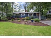 Charming blue home featuring a well-manicured lawn, mature trees and welcoming front entrance at 418 Ridgefield Rd, Chapel Hill, NC 27517