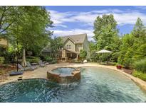 Backyard pool and spa with landscaped patio area offers great outdoor living and entertainment space at 4221 Bibleway Ct, Holly Springs, NC 27540