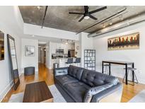 Open-concept living area with modern furnishings, concrete ceiling, and hardwood floors at 444 S Blount St # 209, Raleigh, NC 27601