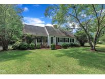 Charming single-story home with manicured lawn, lush landscaping, and inviting front porch at 705 Wilsons Mills Rd, Smithfield, NC 27577