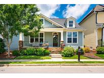 Charming light blue home featuring dormer windows, a cozy front porch, and beautifully landscaped yard at 104 Treywood Ln, Chapel Hill, NC 27516