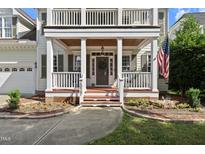Inviting front porch with white columns, railing, and a charming entrance featuring a wreath and American flag at 2027 River Grove Ln, Knightdale, NC 27545