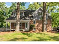Charming two-story home featuring a brick facade, gray siding, and inviting front porch nestled among mature trees at 205 Northfield Dr, Raleigh, NC 27609