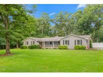Traditional-style home featuring a lush green lawn, mature trees, and a welcoming front porch with an American flag at 3315 Swepsonville Saxapahaw Rd, Graham, NC 27253
