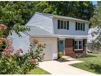 Charming two-story home featuring a brick facade, blue door, landscaped yard, and an attached one car garage at 505 Drolmond Dr, Raleigh, NC 27615