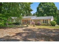 Charming single-story home featuring a welcoming covered porch, complemented by mature trees and beautiful landscaping at 6022 Little Creek Church Rd, Clayton, NC 27520