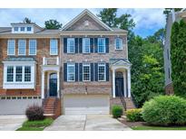 Inviting brick townhome featuring a two-car garage and meticulously landscaped front yard at 8715 Macedonia Lake Dr, Cary, NC 27518