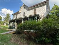Two-story home featuring an accessible ramp and a screened-in porch, set amid mature foliage at 94 Bynum Church Rd, Pittsboro, NC 27312
