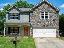 Charming two-story home featuring stone accents, green shutters, manicured lawn, and inviting front porch at 1122 Birkdale Dr, Mebane, NC 27302