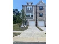Attractive brick townhome featuring an attached two-car garage and well-manicured lawn at 1909 Fishamble St # 16, Fuquay Varina, NC 27526