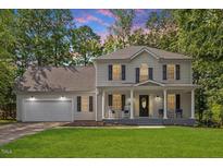 Charming two-story home featuring a welcoming front porch with rocking chairs and a well-manicured lawn at 1990 Ferbow St, Creedmoor, NC 27522