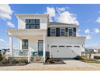 Two-story home featuring a welcoming front porch, a two-car garage, and a blend of white and black siding at 324 Catheys Creek Cir, Wendell, NC 27591