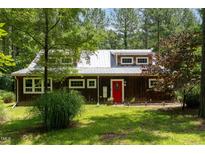 Charming wood home features a red front door, metal roof, and beautifully landscaped front yard at 3822 Chicken Bridge Rd, Pittsboro, NC 27312