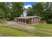 Charming single-story home featuring a cozy front porch and beautiful mature trees at 394 Flanagan Rd, Henderson, NC 27537