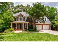 Stunning brick home with mature trees, green lawn, and a spacious driveway leading to an attached two-car garage at 5123 Richland Dr, Raleigh, NC 27612