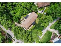 An aerial view shows a house with a large roof nestled in lush greenery at 5301 Thayer Dr, Raleigh, NC 27612