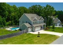 Beautiful two-story home featuring a swimming pool, well-manicured lawn, and an attached two-car garage at 8341 Running Fern Way, Willow Springs, NC 27592
