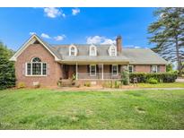 Charming brick home featuring a welcoming front porch, dormer windows, and a well-manicured lawn at 100 Martindale Dr, Youngsville, NC 27596