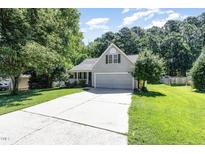 Charming home with a two-car garage, a well-maintained lawn, and mature landscaping at 112 Avent Pines Ln, Holly Springs, NC 27540