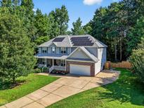 Charming two-story home featuring solar panels, a covered front porch, a two-car garage, and a long driveway at 1205 Magnolia Hill Rd, Garner, NC 27529