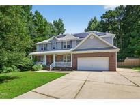 Inviting two-story home with a brick and siding exterior, solar panels, and attached two-car garage at 1205 Magnolia Hill Rd, Garner, NC 27529
