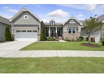 Charming home featuring a well-manicured lawn, a two-car garage and a welcoming front porch at 129 Damsire Way, Cary, NC 27513